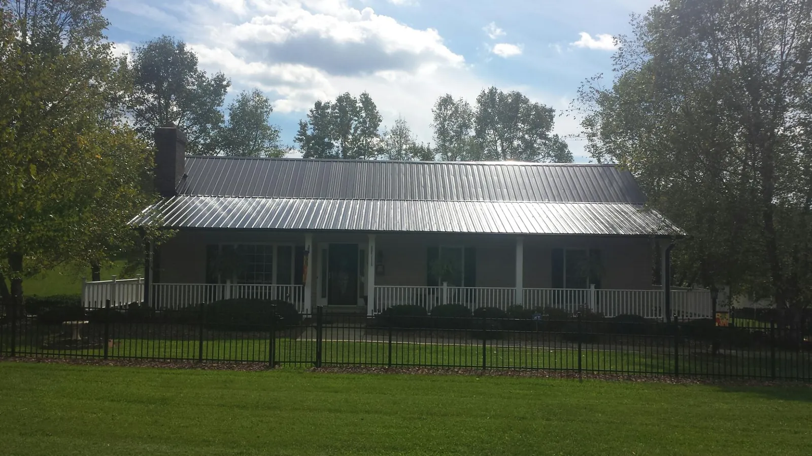 Gray metal roof on a brick ranch with a full width front porch — Gutter Guard Installation work by our crew in Glencoe